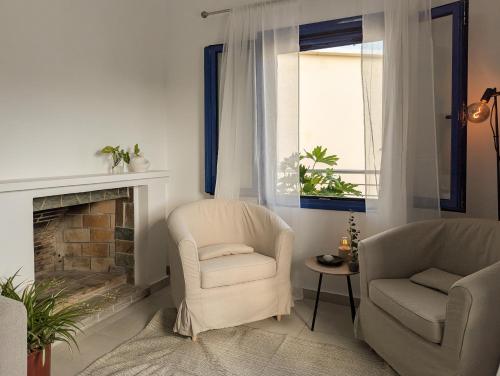 a living room with two chairs and a fireplace at Blue White House in Tourlotí