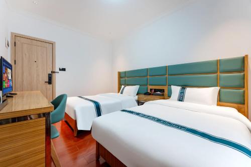 a hotel room with two beds and a desk at 锦泰酒店--广州市十三行南方大厦国际电子城店 in Guangzhou