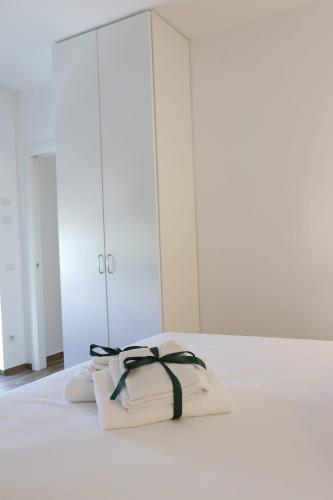 a white bed with two white towels with a black ribbon at Domus Mamurra in Formia