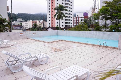 a swimming pool with two lounge chairs on a building at Menlia Guarujá in Guarujá