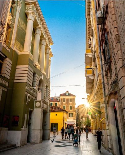 a group of people walking down a street between buildings at Calma Luxury Rooms in Split