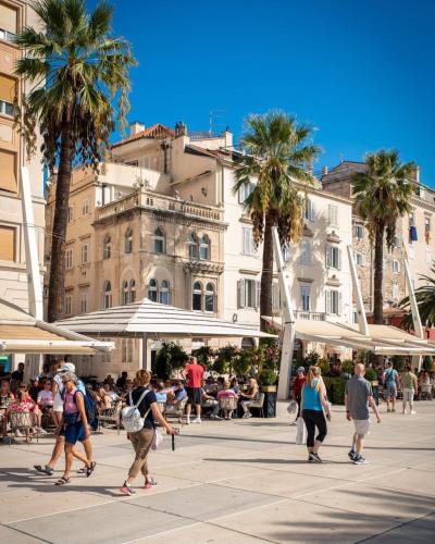 a group of people walking on a street with palm trees at Calma Luxury Rooms in Split