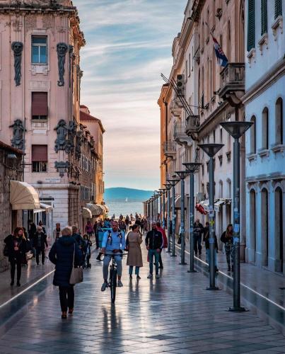 a group of people walking down a street with buildings at Calma Luxury Rooms in Split