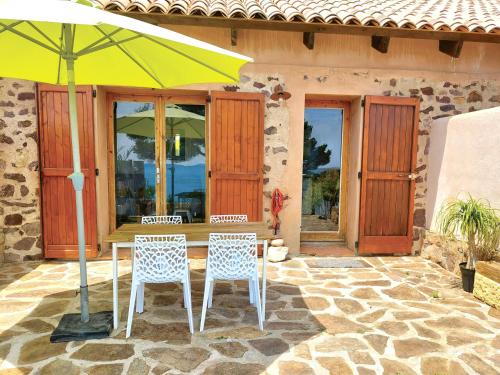 - une table et des chaises sous un parasol sur la terrasse dans l'établissement Maisonnette vue mer, à Carqueiranne