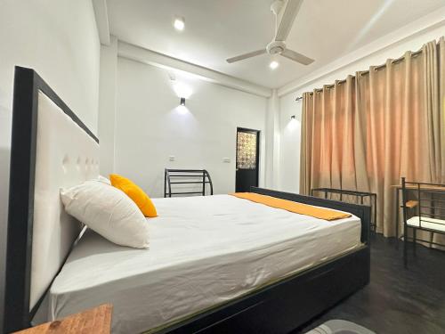 a bedroom with a bed with white sheets and yellow pillows at Large 4 Bedroom Spacious Apartment in Nugegoda, Colombo in Nugegoda