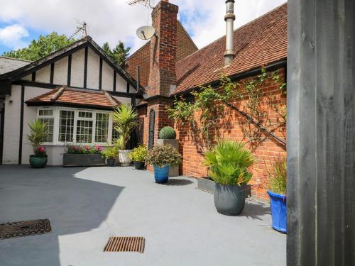 a brick house with potted plants in front of it at Woodend Annexe in Slindon