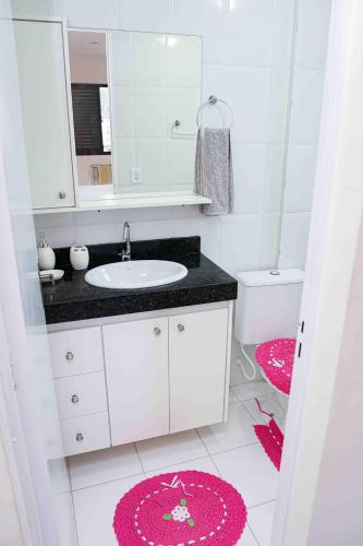 a bathroom with a sink and a mirror and a pink rug at Menlia Guarujá in Guarujá