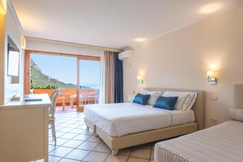 a hotel room with two beds and a balcony at Boutique Hotel Torre Di Cala Piccola in Porto Santo Stefano