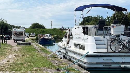a boat is docked in the water with a bike on it at L'Amazone - bateau à quai sur le canal de bourgogne in Tanlay