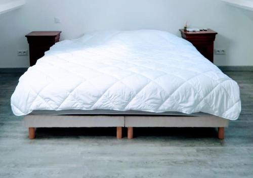 un lit blanc assis dans une chambre avec deux tables de nuit dans l'établissement Maison au calme proche Disneyland Paris 35mn, à Villeneuve-Saint-Denis