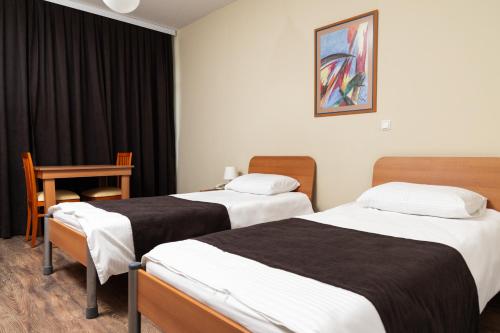 a hotel room with two beds and a table at Hotel Luxor in Pristina