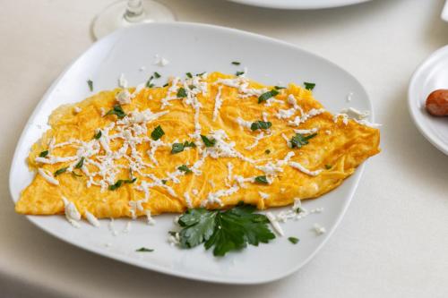 a white plate with an omelet on a table at Hotel Luxor in Pristina