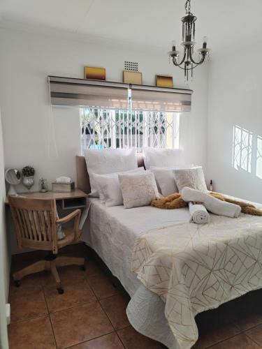a bedroom with a bed and a desk and a window at Saint Blaize Cottage in Boksburg