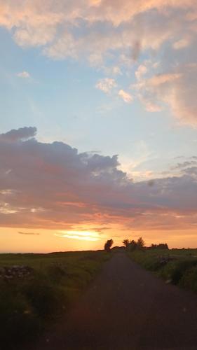 a dirt road with the sunset in the background at Basic, Warm, Cosy, Private Little Chalet in Caherphuca