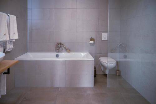 a white bathroom with a tub and a toilet at The Velvet Lodge in The Hague