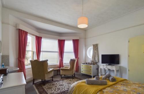 a bedroom with a bed and two chairs and a television at Spectacular sea view double, with exclusive bathroom & use of patio and bike store in Margate