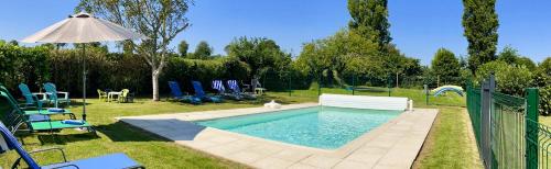 a swimming pool in a yard with chairs and an umbrella at Wisteria Gites in Saint-Denis-de-Gastines