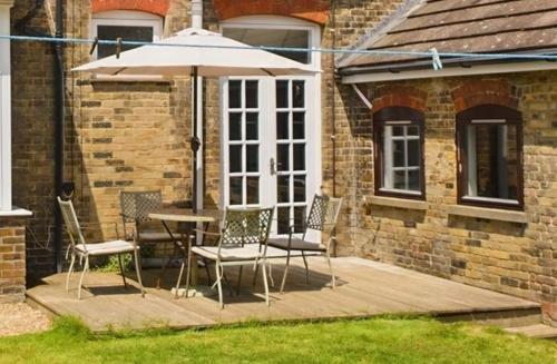 a patio with a table and chairs and an umbrella at Spectacular sea view double, with exclusive bathroom & use of patio and bike store in Margate