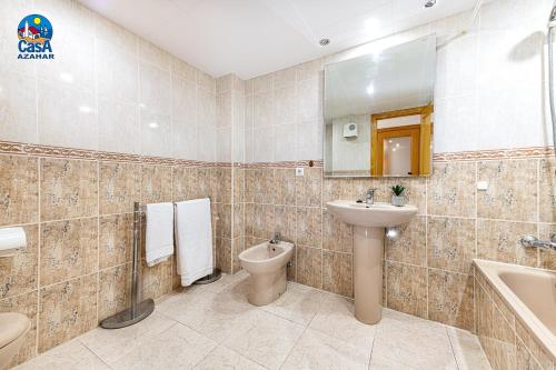 a bathroom with a sink and a toilet and a mirror at Apartamentos Fuentemar Casa Azahar in Alcossebre