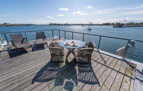a deck with a table and chairs on the water at Waterfront in Olpenitz