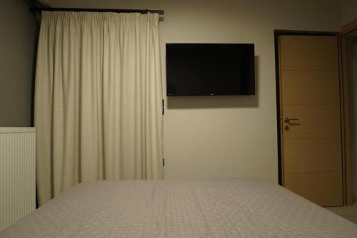 a bedroom with a bed and a television on the wall at SEA LA VIE Apartments & Maisonette in Livanátai