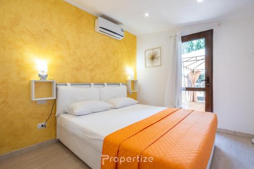 a bedroom with a large bed with an orange blanket at Tra I Verdi Pini by Propertize in Capoterra