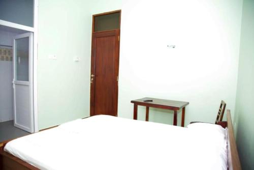 two beds in a room with a door and a table at Joleen Safari Park in Dar es Salaam