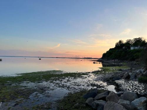 a beach with rocks and the ocean at sunset at Charmerende hus i idylliske Lynæs in Hundested