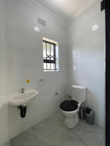 a white bathroom with a toilet and a sink at The Extension in Umtali