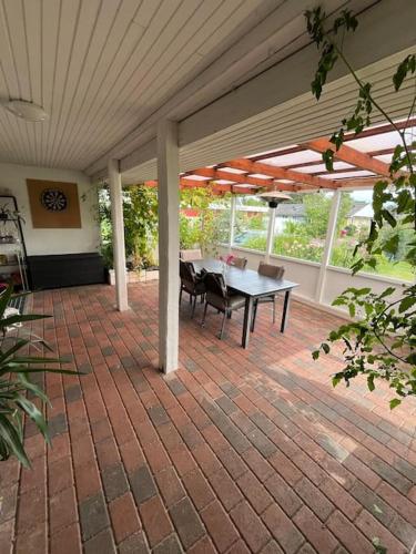 a patio with a table and chairs under a roof at Charmerende hus i idylliske Lynæs in Hundested