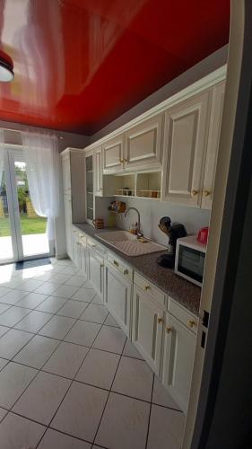 d'une cuisine avec des placards blancs et un plafond rouge. dans l'établissement maison de soleil, à Étaples