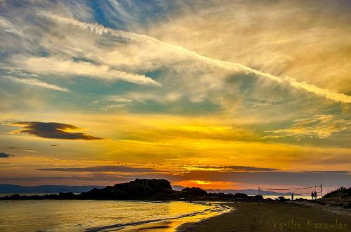 a sunset on a beach with a cloudy sky at Brati II Beach Hotel in Arkoudi