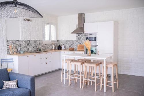 LOU DESTRE Maison 3 Chambres, parking vélo, Châteauneuf-du-Pape في شاتونوف-دو-باب: مطبخ مع خزائن بيضاء وطاولة وكراسي