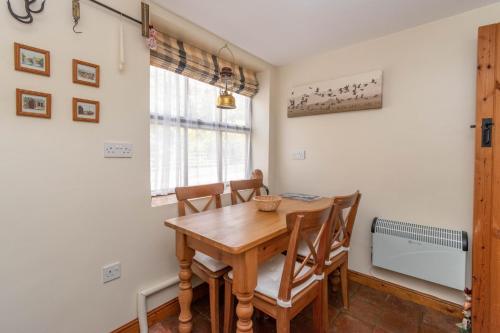 a dining room with a wooden table and chairs at Post Box Cottage in Stiffkey