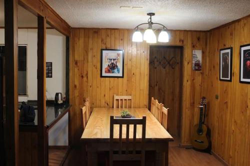 a dining room with a wooden table and a guitar at Alojamiento Casa completa en Puerto Montt in Puerto Montt