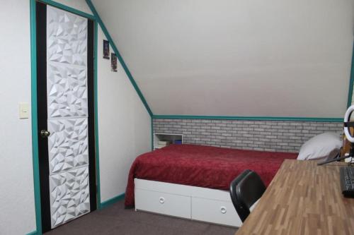 a bedroom with a bed with a red bedspread at Alojamiento Casa completa en Puerto Montt in Puerto Montt