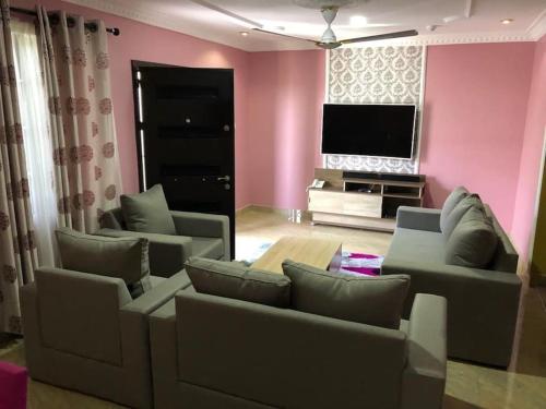 a living room with two couches and a flat screen tv at Serene 2 bed with Wi-Fi and AC in Madina