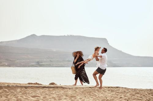 a group of people walking on the beach at Arina Beach Resort in Kokkíni Khánion