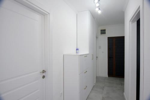 a white hallway with white cabinets and a black door at Venima City Center Apartment in Tivat