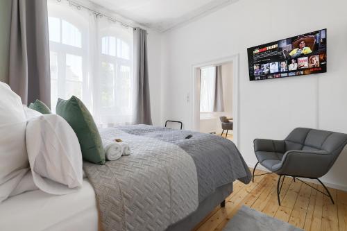 a white bedroom with a bed and a chair at Apart21 - Exclusive Apartments in Central location with Parking in Ingolstadt