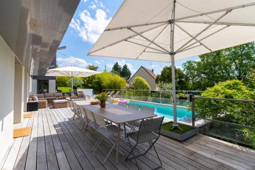 une terrasse en bois avec une table et un parasol dans l'établissement Villa d'exception M54 Vouvray à 2H au sud de Paris proche Amboise Chenonceau Chambord, à Vouvray