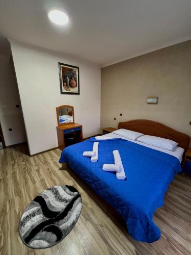 a bedroom with a blue bed with two slippers on it at Motel Krstac in Mojkovac