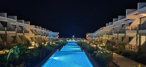 una vista de una piscina por la noche en Pearl Island apartments, en Kalogrea
