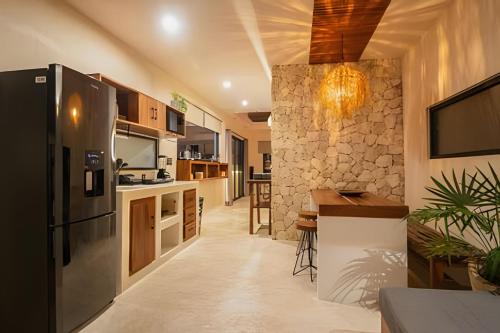 a kitchen with a black refrigerator and a stone wall at Casa de Piedra - Departamentos Bacalar- in Bacalar