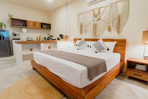 a bedroom with a large bed and a kitchen at Nómadas Bacalar- Departamentos - in Bacalar
