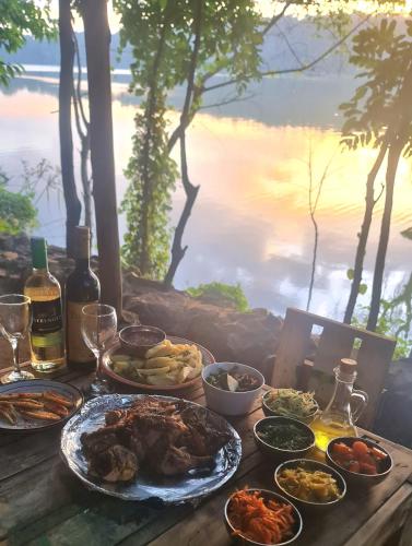 a table with food and bottles of wine and a view of the water at Holiday cottage by the river, Arusha in Arusha
