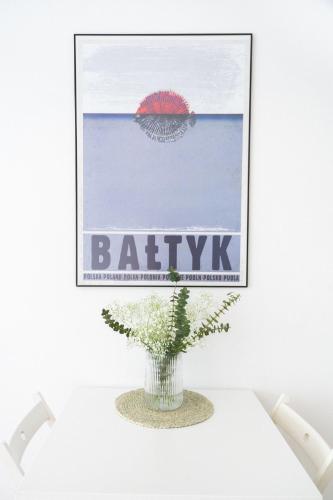 a vase with a plant on a table with a picture at Domki Wierzbówka in Mielno