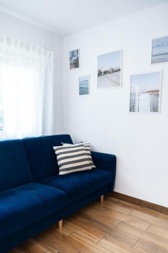a blue couch in a living room with pictures on the wall at Domki Wierzbówka in Mielno