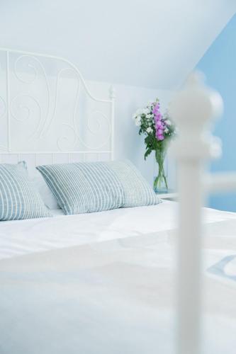 a white bed with a vase of flowers on it at Domki Wierzbówka in Mielno