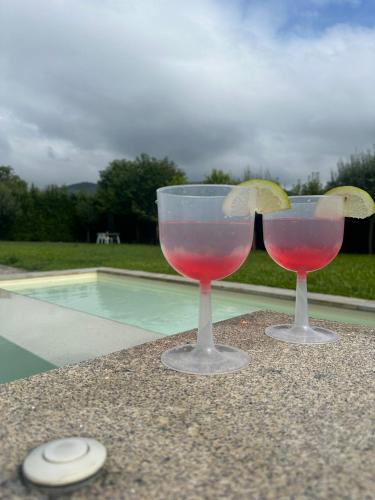 two wine glasses sitting next to a swimming pool at Quinta dos Sonhos in Valbom